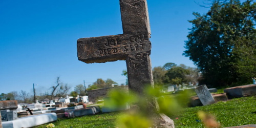 Weathered stone cross headstone at graveyard