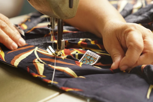 Hands sewing printed fabric on vintage sewing machine