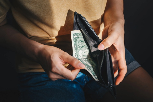 Hands pulling single dollar bill out of empty wallet