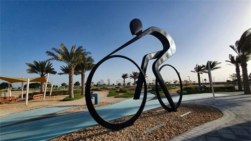 Abstract metal cyclist sculpture in palm-tree waterfront park