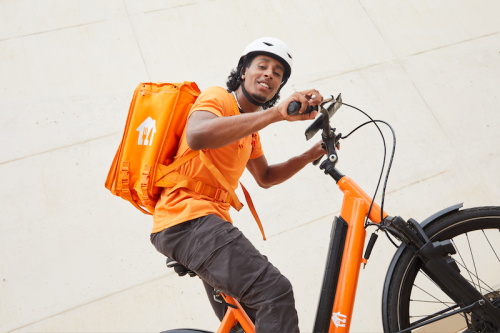 Food delivery rider riding orange electric cargo bicycle