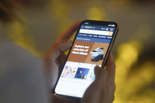 Hands holding smartphone showing Amazon mobile shopping page